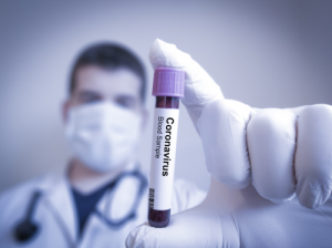 a man holding a vial of blood labeled COVID-19